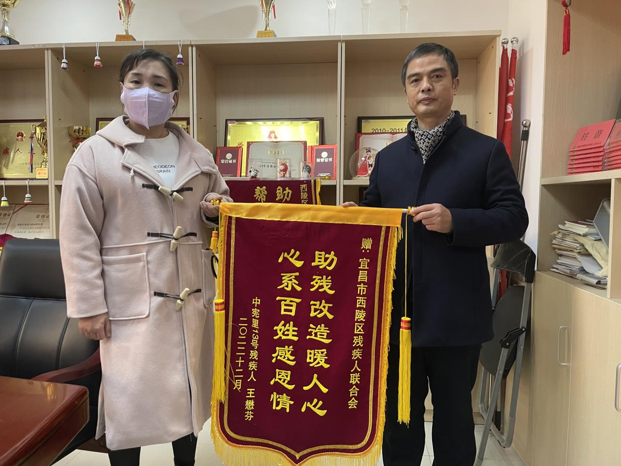 图为林惜梅（左）向区残联理事长王毅（右）捐赠锦旗